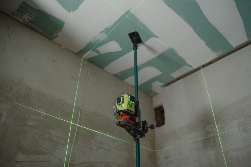 pexels-photo-6473973 A laser level tool in action at an indoor construction site with marked walls.
